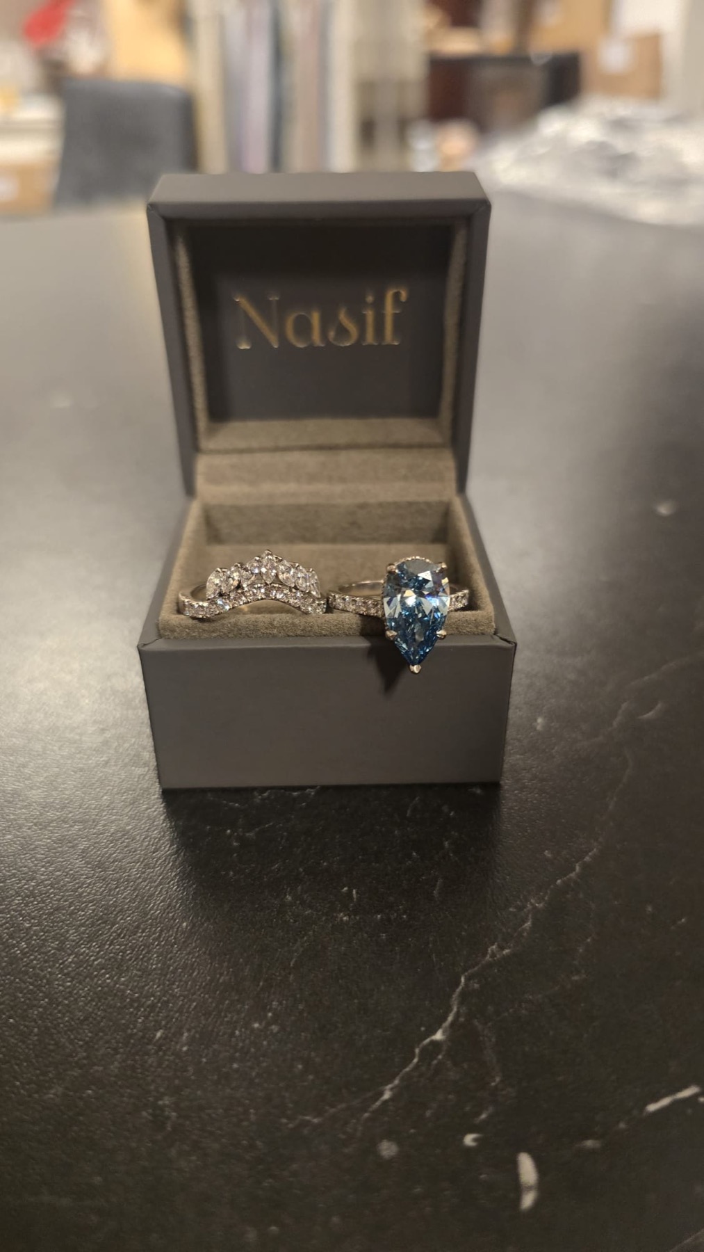 Blue pear-cut diamond engagement ring with matching band in a Nasif box